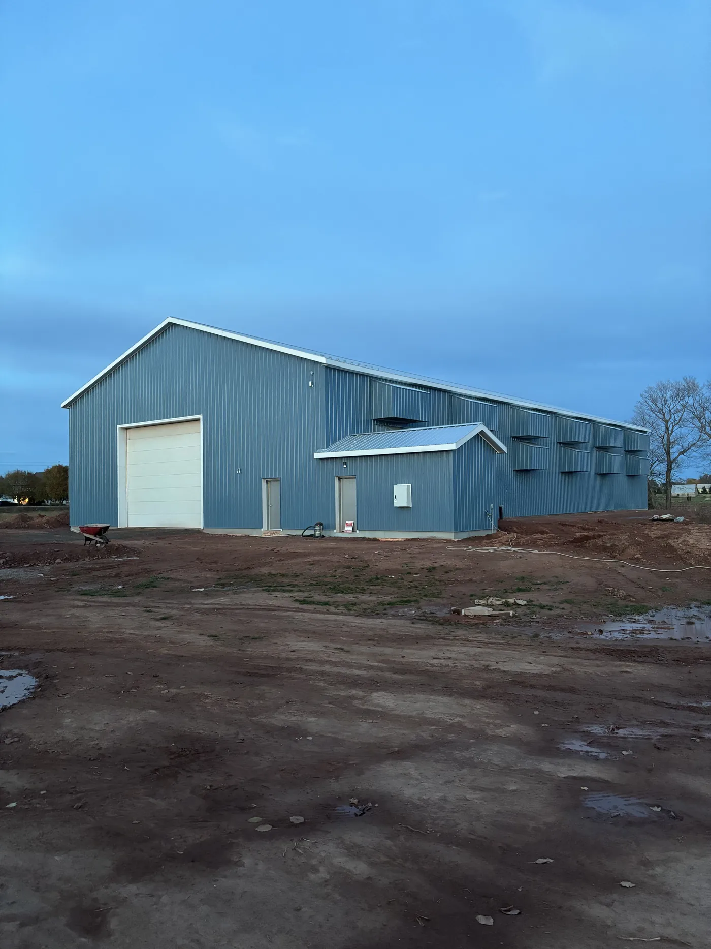 A finished blue steel farm building under a clear sky