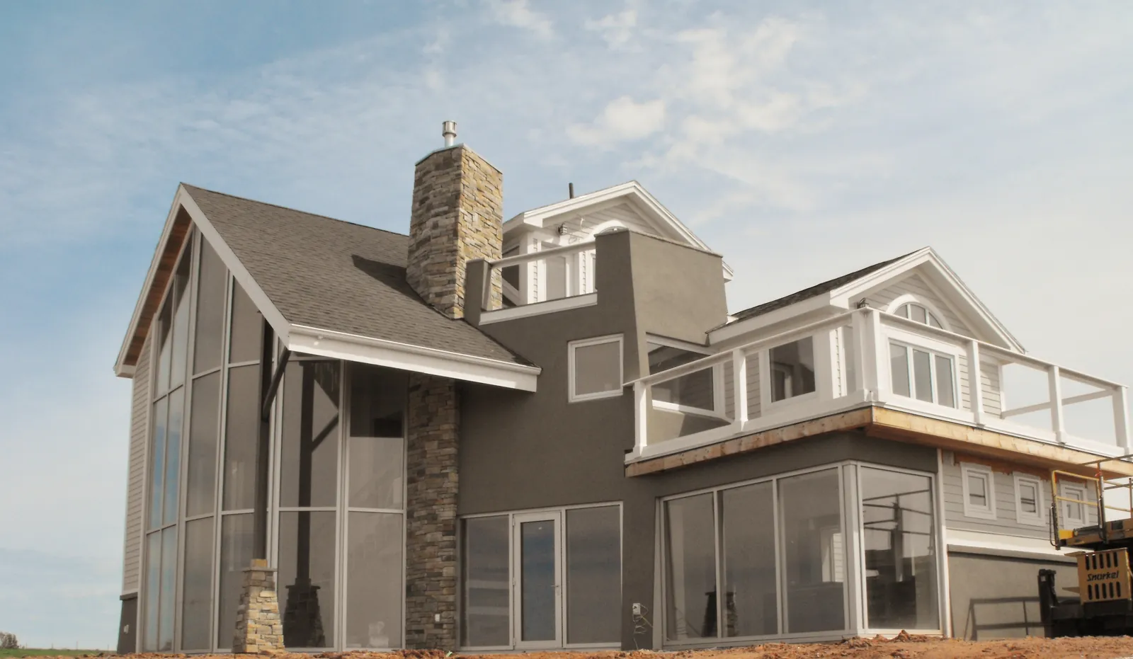 A finished two-storey home with a stone chimney and glass gable