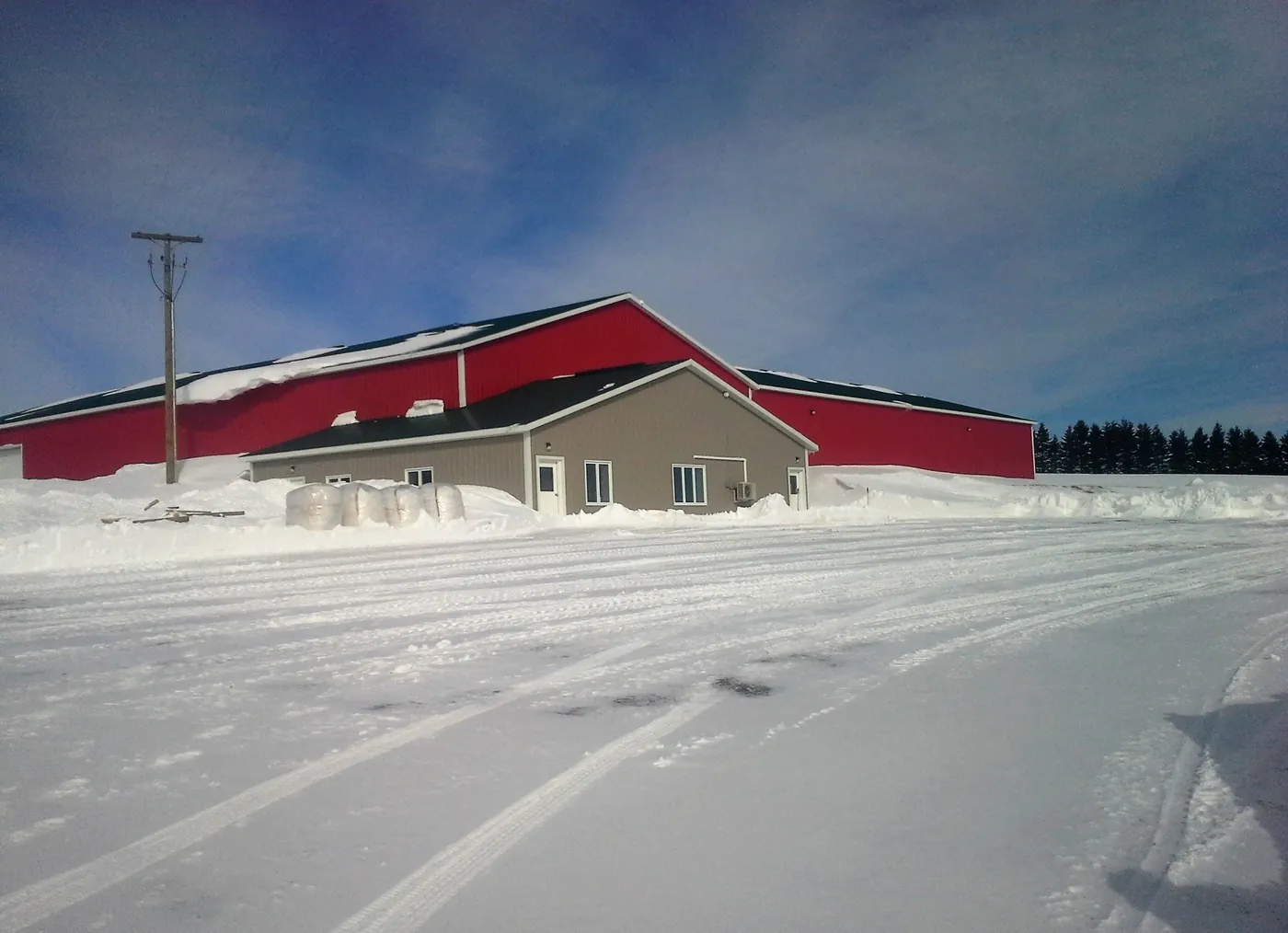 A finished potato storage building with a red roof, in winter